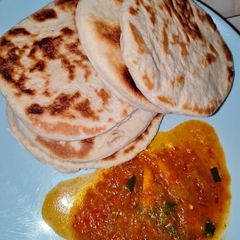 A picture of Naan bread with pumpkin soup.