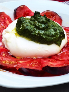 Una foto de Ensalada de burrata, tomate azul y pesto de almendras