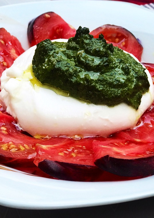 Una foto de Ensalada de burrata, tomate azul y pesto de almendras