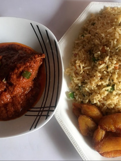 A picture of Stir fried rice, chicken stew and fried plantain.