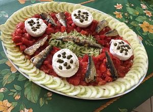 Une photo de Salade de tomates, courgette et concombre aux sardines, câpres et mozzarella sauce malt