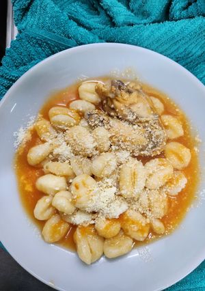 Una foto de Ñoquis de papa con salsa y alitas de pollo