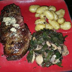 A picture of Bone-in Prime rib with red chard, and mini golden potatoes.