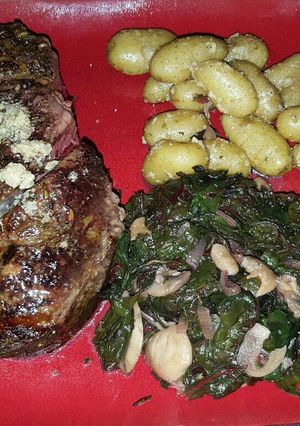 A picture of Bone-in Prime rib with red chard, and mini golden potatoes.