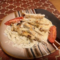 A picture of Chicken over garlic Parmesan spaghetti.