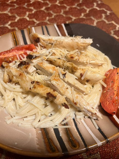 A picture of Chicken over garlic Parmesan spaghetti.