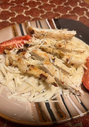 A picture of Chicken over garlic Parmesan spaghetti.
