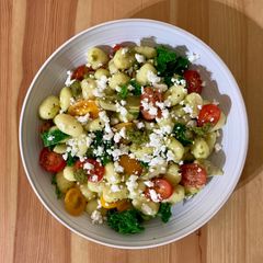 A picture of Gnocchi with pesto, artichoke, tomatoes and feta.