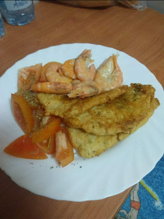 Una foto de Merluza rebozada con langostinos y ensalada de tomate al orégano