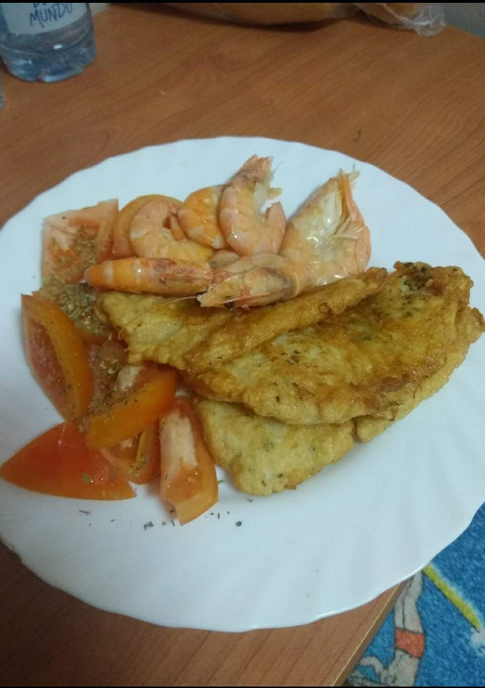 Una foto de Merluza rebozada con langostinos y ensalada de tomate al orégano