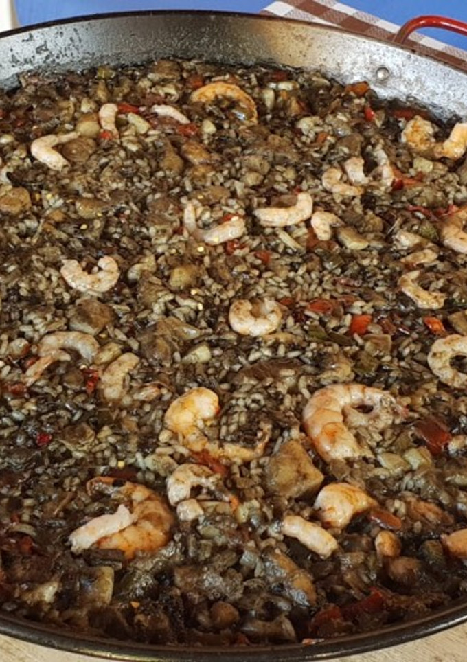 Una foto de Arroz negro con rape y calamar al alioli a la leña