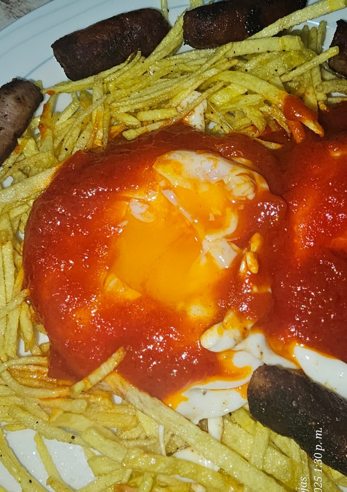 Una foto de Huevos fritos con patatas paja, salsa de tomate y salchichas