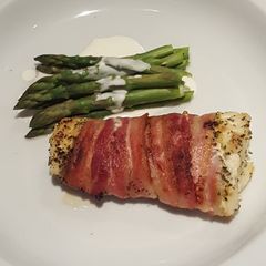 A picture of Roasted white fish wrapped in smoked bacon with asparagus.