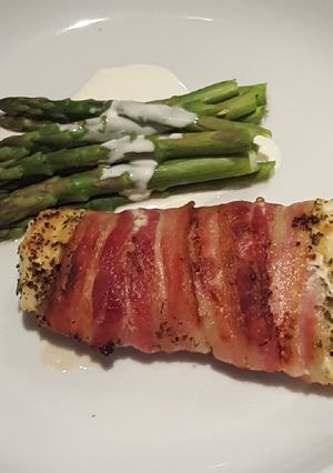 A picture of Roasted white fish wrapped in smoked bacon with asparagus.