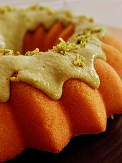 Una foto de Bundt cake genovés de coco con cobertura de crema de pistachos y chocolate blanco (sin gluten)