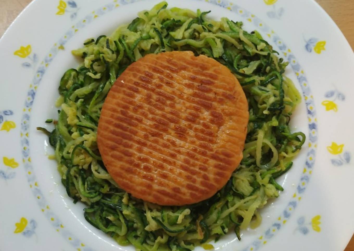 Hamburguesa de salmón y merluza en cama de calabacín
