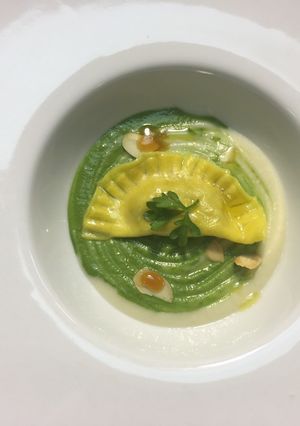 A picture of Classic Pumpkin Raviolo with Cauliflower Cream, Zucchini, and Almonds.