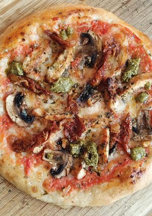 Una foto de Pizza de pollo cajún con champiñones y tomate seco con toque de pesto