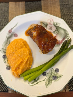 Una foto de COSTILLAS BBQ con puré de camote y espárragos