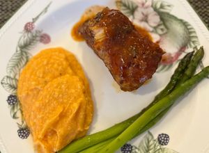Una foto de COSTILLAS BBQ con puré de camote y espárragos