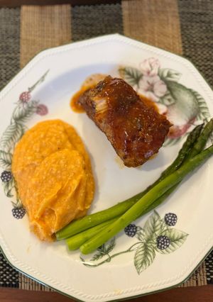 Una foto de COSTILLAS BBQ con puré de camote y espárragos