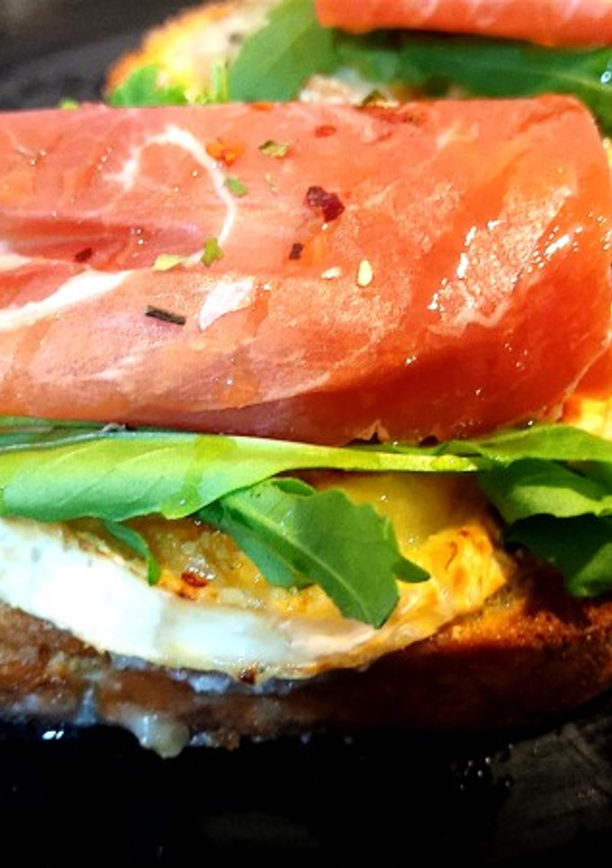 Una foto de Tosta de rulo de cabra con rúcula y jamón