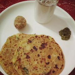 A picture of Aloo paratha with buttermilk and dry fruit ladoo.