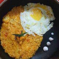 A picture of Tomato basil almond risotto with prawns and egg.