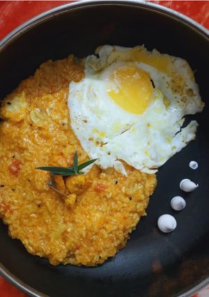 A picture of Tomato basil almond risotto with prawns and egg.