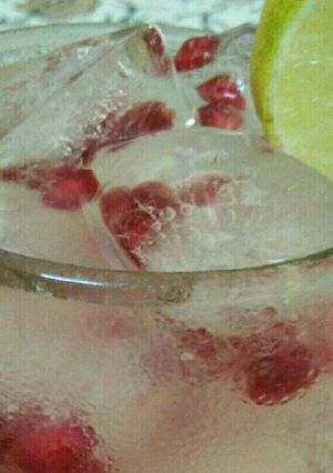 A picture of Lemon water with pomegranate icecubes.