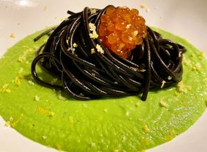 Foto di Spaghetti al nero di seppia con uova di salmone e scorza di limone su crema di piselli