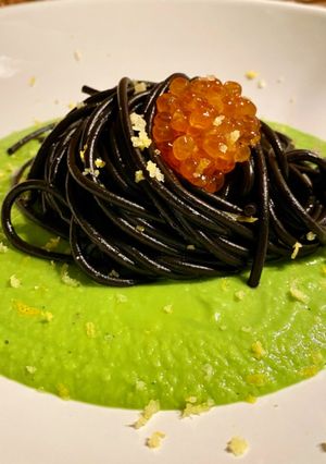 Foto di Spaghetti al nero di seppia con uova di salmone e scorza di limone su crema di piselli