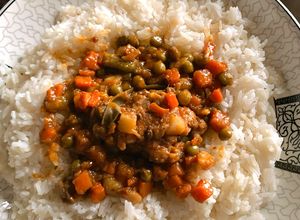 Une photo de Poulet à la tomate et petits pois, servi avec du riz
