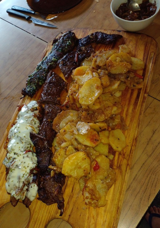 Una foto de Entraña confitada con guarnición de papas, cebolla y morrón