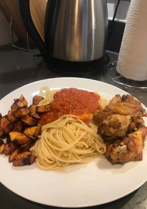 A picture of Spaghetti and fried pepper sauce with wings and plantain.