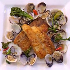 A picture of Pan fried sea bream with sake braised clams and broccolini.