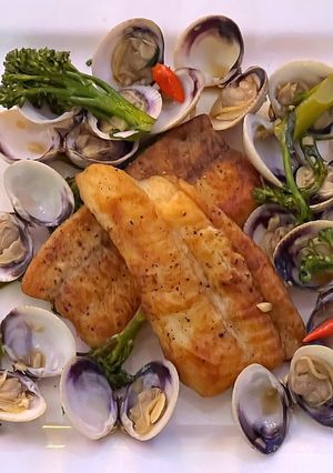 A picture of Pan fried sea bream with sake braised clams and broccolini.