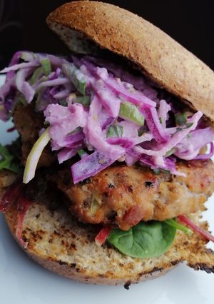 A picture of Pork and chorizo bagel burger + pickled cabbage and apple slaw.