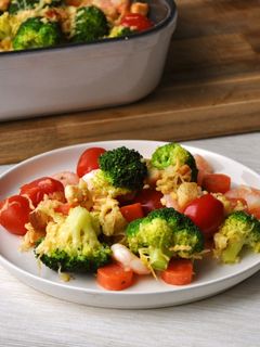 Una foto de Camarones gratinados con brócoli, zanahorias y tomates cherry
