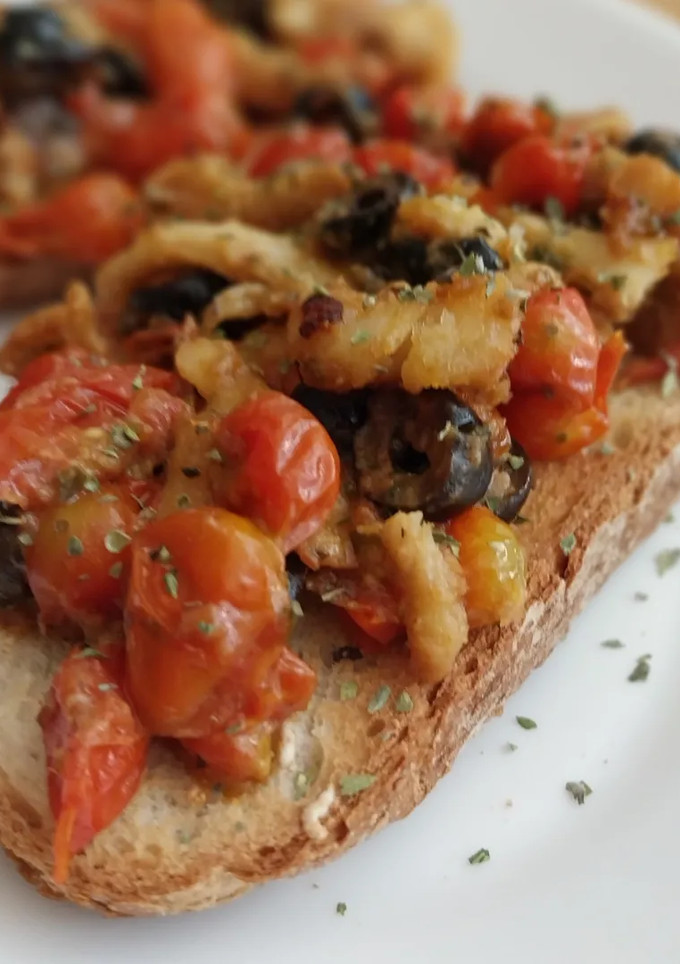Una foto de Tosta de bacalao, ajo escalivado y tomates cherry con mostaza