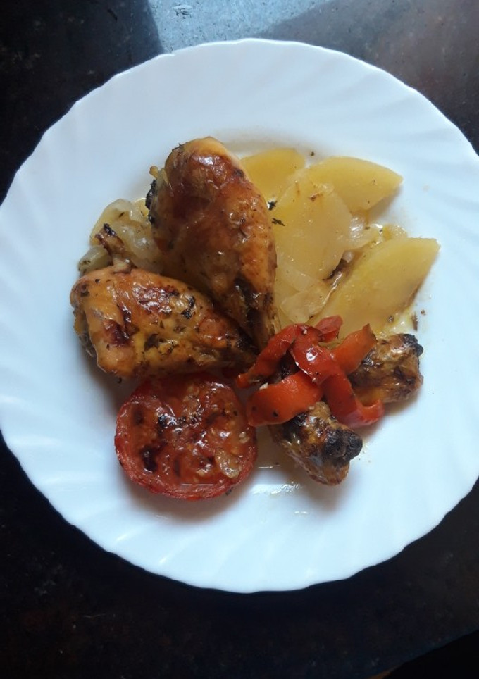 Una foto de Muslos de pollo al horno con tomates y patatas