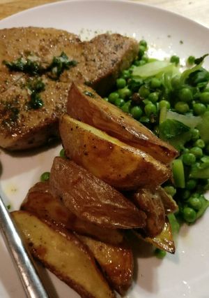 A picture of Tuna steaks, rough cut potato and greens.