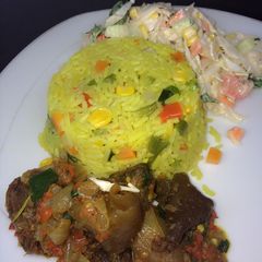 A picture of Fried rice with peppered goat meat and coleslaw.
