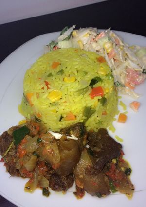 A picture of Fried rice with peppered goat meat and coleslaw.