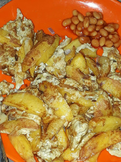 A picture of Chips and egg with baked beans.