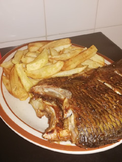 A picture of Grilled Bream fish and fried potato chips.