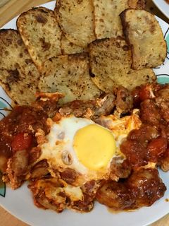 Una foto de Butifarra con salsa de tomate picante, huevos y patatas al horno