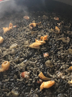 Una foto de Arroz negro de sepia, calamares y gambones