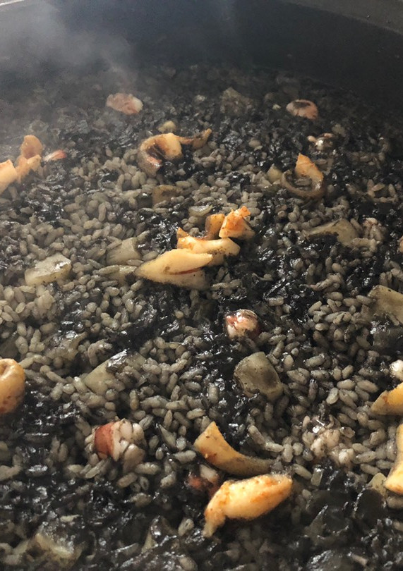 Una foto de Arroz negro de sepia, calamares y gambones