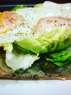 Una foto de Huevos fritos sobre chapata bañada en salsa pesto